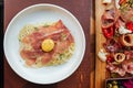 Top view of Fettuccine Carbonara with parma ham and yolk with black pepper. Served in white plate with Cold Cuts