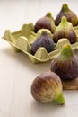 Top view of figs in yellow egg carton, with selective focus, on white wooden table Royalty Free Stock Photo