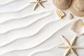Top view of fine white sand with ripple patterns, framed by straw hats, sea shells, and two light beige starfish in the top right Royalty Free Stock Photo