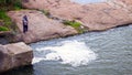 Top view of fisherman who fishes with a fishing rod in river from a gentle rocky shore