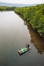 Top view, fishermen with traditional crab trap sitting on boat in the river of mangrove forest. Little home and mountains