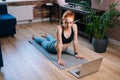 Top view of fit smiling redhead young woman lying on floor and using laptop computer at apartment