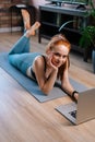 Top view of fit smiling redhead young woman lying on floor and using laptop computer at apartment Royalty Free Stock Photo