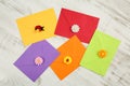 Top view of five colorful envelopes from recycled paper with decorative flower petals and ladybugs on white wooden background. Royalty Free Stock Photo