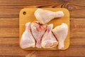 Five pieces fresh raw chicken legs on a bamboo chop board