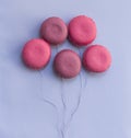 Top view, five pink almond cookies in the form of balloons on a lilac background