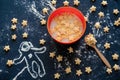 bowl of milk with corn pads in the shape of stars and a silhouette of an astronaut made of flour on a black