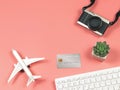 Flat lay of airplane model, credit card, computer keyboard,  camera and cactus on pink background, business and traveling concept Royalty Free Stock Photo