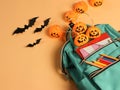 Flat lay  of backpack with school supplies, Halloween pumpkin lights and black paper bats  on orange background. Education and Royalty Free Stock Photo
