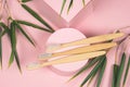 flat lay bamboo tooth brushes on a pink podium with green bamboo leaves