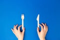 Top view and flat lay of bamboo wooden cutlery isolated on blue background. Female hands holding fork and knife. Zero waste Royalty Free Stock Photo