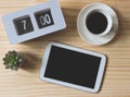 Flat lay of blank black screen digital tablet with flip clock 7 am,  a cup of black coffee and succulent plant pot on wooden Royalty Free Stock Photo