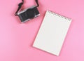 Flat lay of blank page opened notebook and camera on pink background