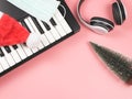 Flat lay of Christmas tree,white headphones , Santa and medical mask on electric piano on pink background with copy space.Covid-19 Royalty Free Stock Photo