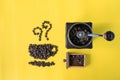 Top view flat lay coffee beans in cup and smell icon shape and vintage wooden coffee grinder on yellow background Royalty Free Stock Photo