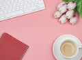 Flat lay of coffee cup  with tulip flower bouquet, red diary  and computer keyboard on pink background with copy space for text. Royalty Free Stock Photo