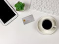 Flat lay of Credit card, computer keyboard, digital tablet, a cup of black coffee, succulent plant pot on white background with Royalty Free Stock Photo