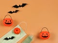 Flat lay of Halloween pumpkin , black paper bats,medical mask and alcohol sanitizer gel on orange background. Halloween , COVID-19