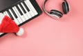 Flat lay of  headphones, Santa hat on electric piano  on pink background with copy space. Christmas party and music Royalty Free Stock Photo