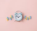 Top view flat lay medicine pills and alarm clock. Beige and blue. Medication time concept