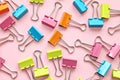 Top view or flat lay of multi colored binder clips on pink background Royalty Free Stock Photo