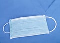One surgical mask laying on blue scrub top
