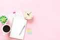 Top view or flat lay of open notebook, clock and coffee cup on pink background with copy space ready for adding or mock up Royalty Free Stock Photo