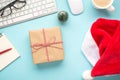 Top view flat lay photo of giftbox with rope bow santa claus hat keyboard computer mouse glasses notepad pen fir toy and cup of Royalty Free Stock Photo