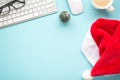 Top view flat lay photo of santa claus hat keyboard computer mouse glasses pine toy and cup of hot drinking on isolated pastel Royalty Free Stock Photo