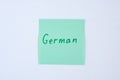 Top view flat lay of the reminder notepaper of green color with word German on it on white background. Flashcards and language