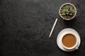 Top view flat lay shot of office desk table. Cup of cappucino coffee, plant pot and pen on dark background. Copy space