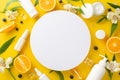 Top view flat lay of skincare products with juicy slices of orange white flowers on bright yellow background