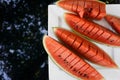 Top view flat lay sliced red watermelon on plate on black glass table with trees in reflection. Summer food, refreshment, vegetari Royalty Free Stock Photo