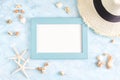 Top view flat lay summer mockup: empty blue photo frame, seashells, straw hat and starfish on blue background. Vacation concept Royalty Free Stock Photo