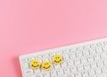 Flat lay of threes yellow circle smiling faces  on white computer keyboard on pink  background Royalty Free Stock Photo