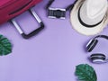 Flat lay of traveler accessories , hat , camera, headphones and pink suitcase on purple background. travel concept Royalty Free Stock Photo