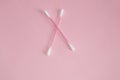 Top view, flat lay, two pink plastic cotton swabs arranged crosswise on a pink background, the concept of cleanliness and hygiene Royalty Free Stock Photo