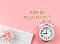 Flat lay of white vintage alarm clock  with bouquet of pink flower on computer keyboard and wooden letter GOOD MORNING  on pink Royalty Free Stock Photo