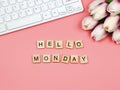Flat lay of wooden letter HELLO MONDAY on pink background with computer keyboard and purple-white tulip bouquet decoration Royalty Free Stock Photo