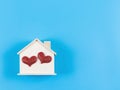 Flat lay of wooden model house with red glitter heart on blue background. dream house , home of love, strong relationship, Royalty Free Stock Photo