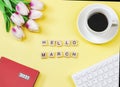 Flat lay of woodeng letters HELLO MARCH , coffee cup ,tulip flower bouquet, red diary2021  and computer keyboard on yellow Royalty Free Stock Photo