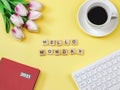 Flat lay of woodeng letters HELLO MONDAY , coffee cup ,tulip flower bouquet, red diary2021  and computer keyboard on yellow Royalty Free Stock Photo