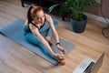 Top view of flexible redhead young woman working out, doing stretching exercise on yoga mat.