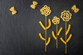 Top view flowers and butterflies made out of various pasta on the dark slate background. Royalty Free Stock Photo