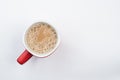 Top view of foamy milk coffee or milk tea in a red mug