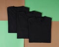 Top view of folded black t-shirt  with colored background  copy space  flat lay. Royalty Free Stock Photo