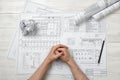 Top view folded hands of man on wooden surface with architect drawing Royalty Free Stock Photo