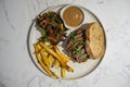 Top View Food Photo of Steak Sandwich with Salad, French Fries and Dip on a White Plate in a Restaurant Royalty Free Stock Photo