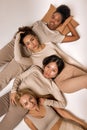 top view on four diverse ladies lying on floor in studio, calm and pacified, isolated