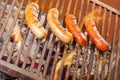 Top view of four grilling sausages on barbecue grill, burning coal with fired. BBQ in the garden. Bavarian sausages Royalty Free Stock Photo